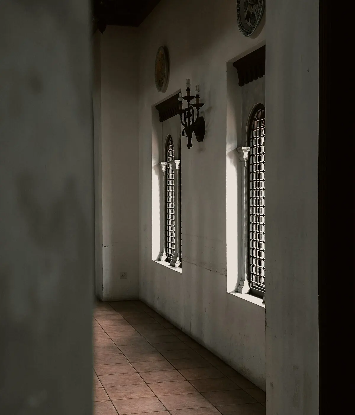 Corredor silencioso de arquitetura clássica, com janelas altas em arco e luz entrando pela lateral